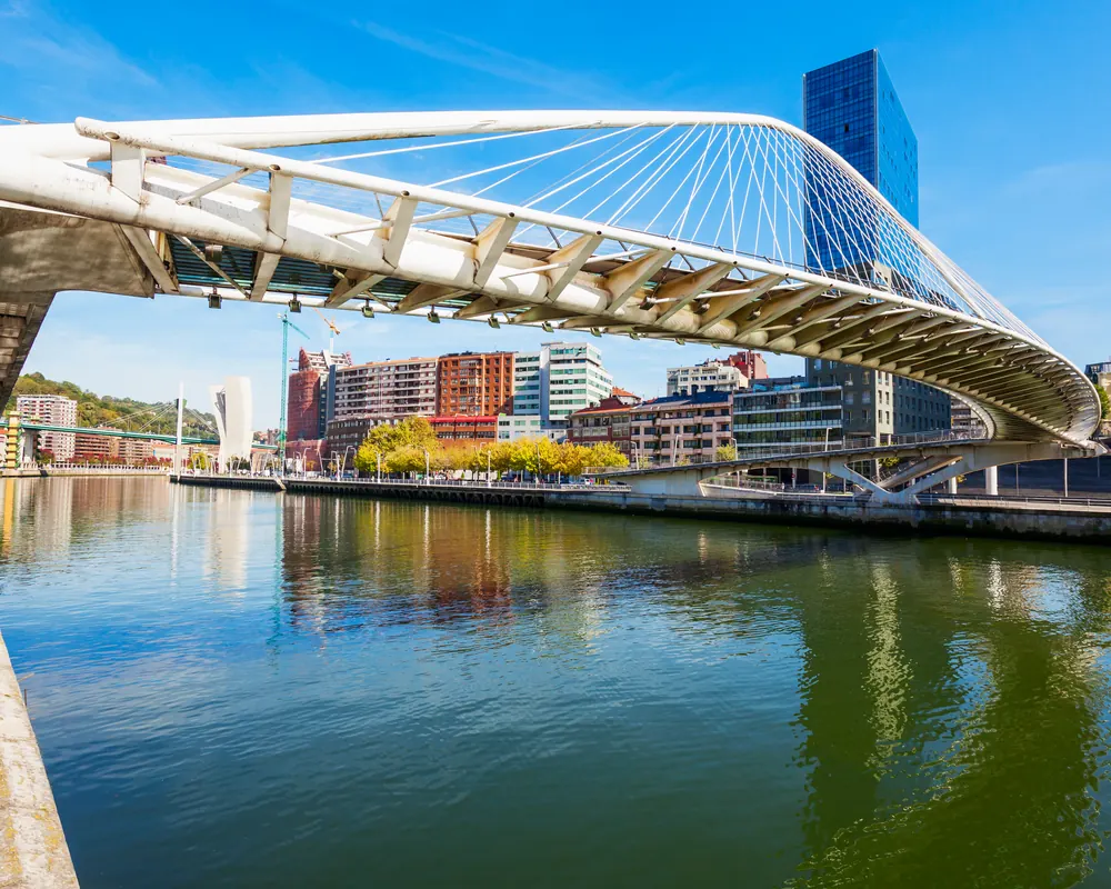 Puente Zubizuri sobre la ría del Nervión en Bilbao con las torres Isozaki al fondo