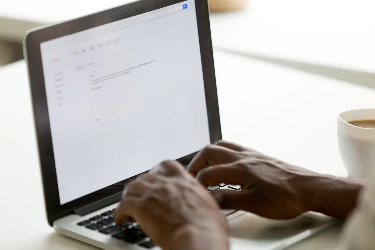 Manos escribiendo un correo electrónico profesional en un portátil